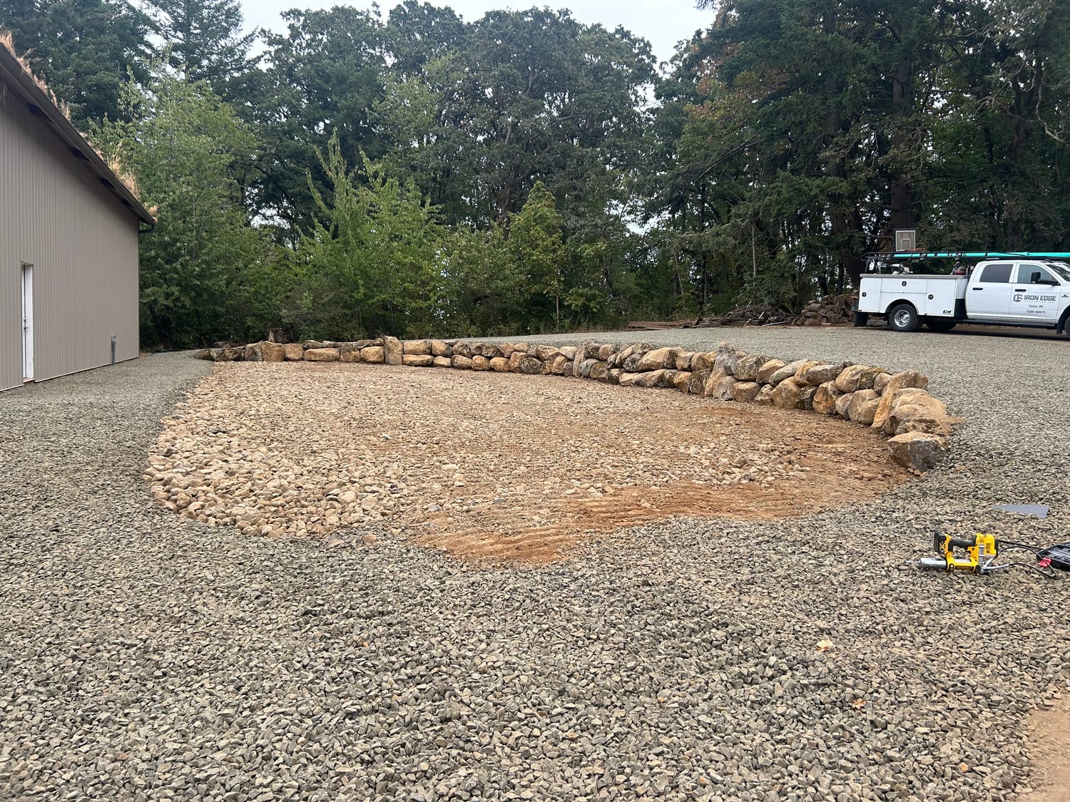 Custom rock wall built from customer supplied boulders around a new gravel pad.