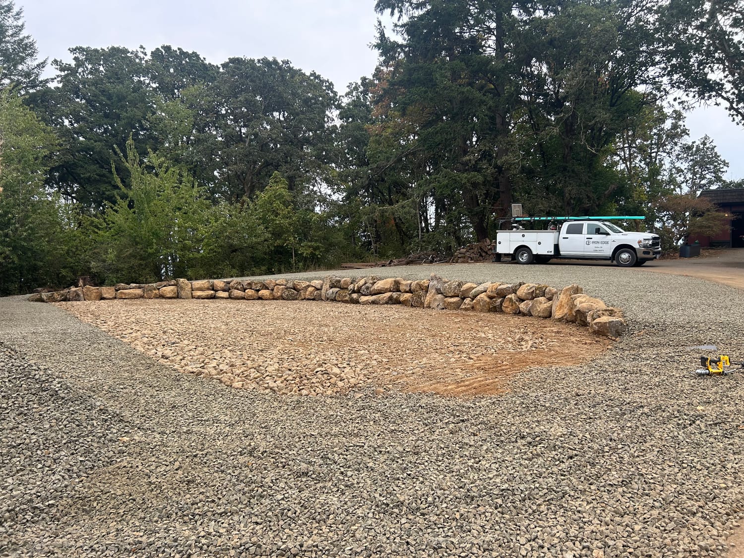 Finished boulder wall wrapping the pad, with the Iron Edge truck on site.